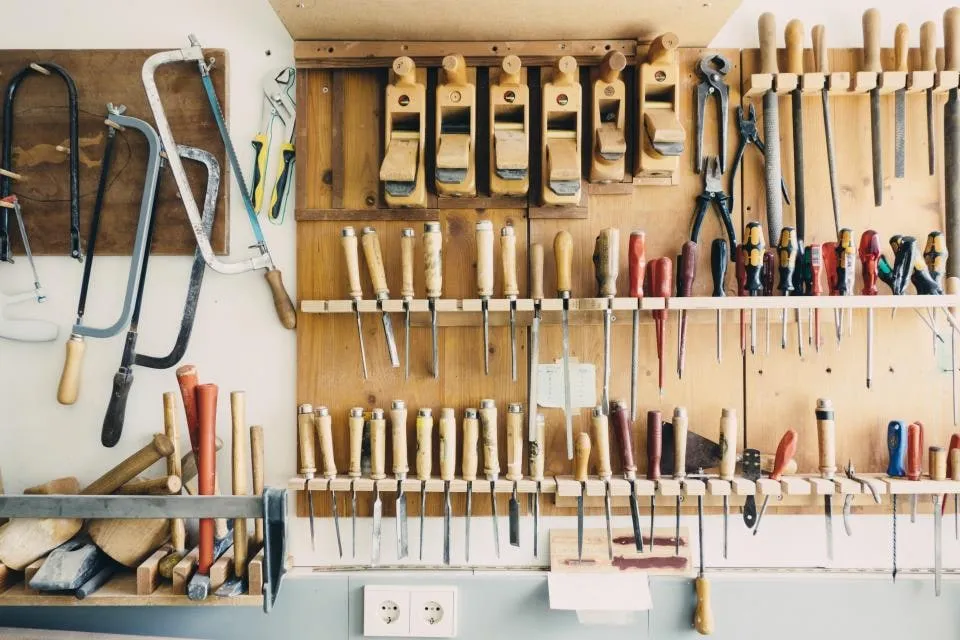 A workshop wall hung with rows of chisels, screwdrivers, planes and saws
